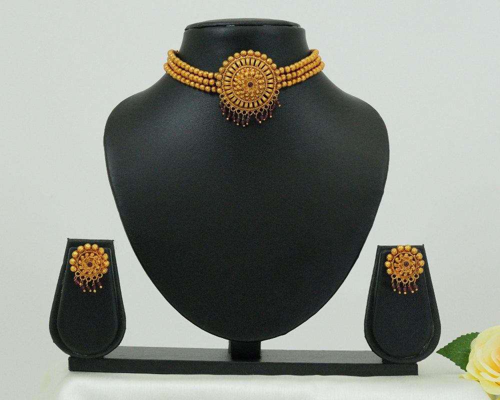 Gold necklace and earrings set on a black mannequin bust